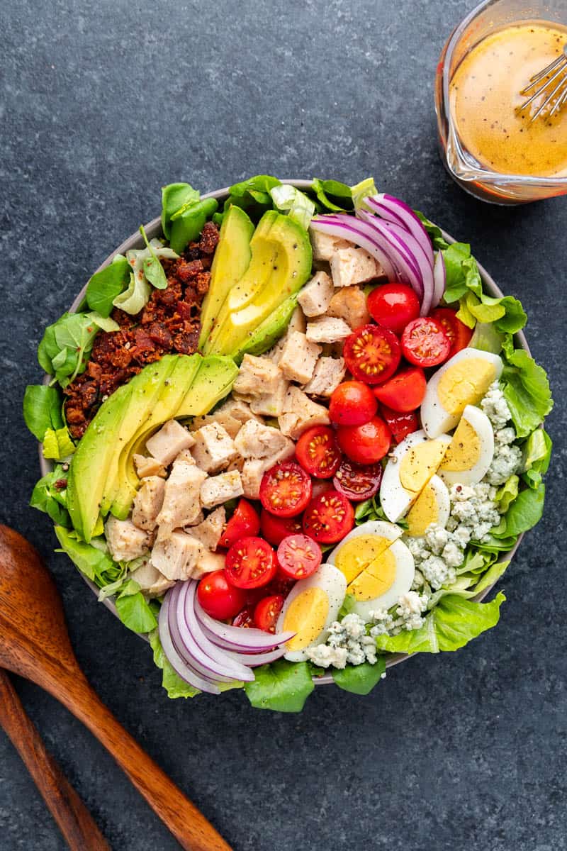 Overhead view of a Cobb Salad with dressing on the side.