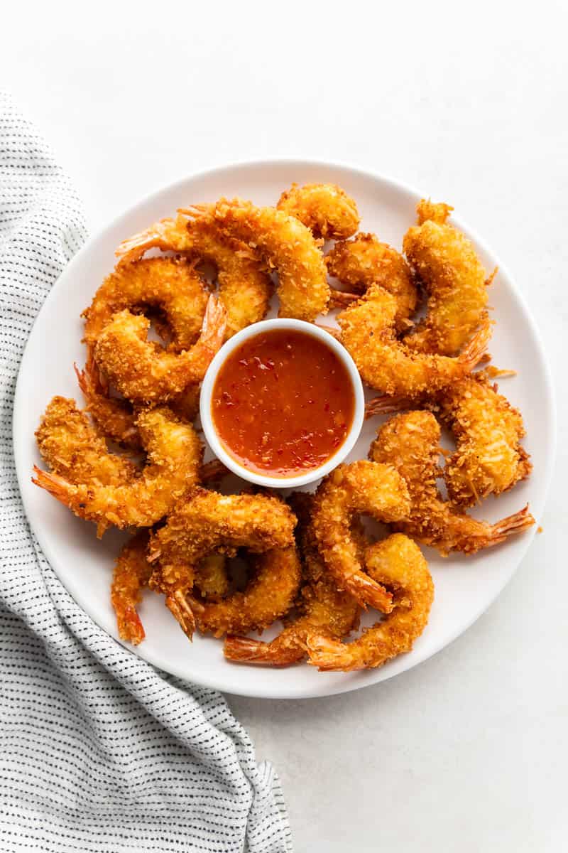 Overhead view of crispy coconut shrimp and dipping sauce on a serving platter.