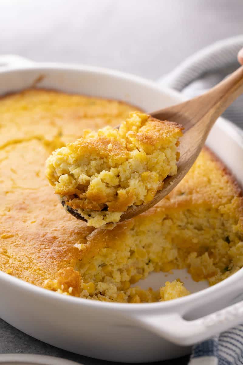 Corn casserole with a wooden spoon. Remove some for serving.