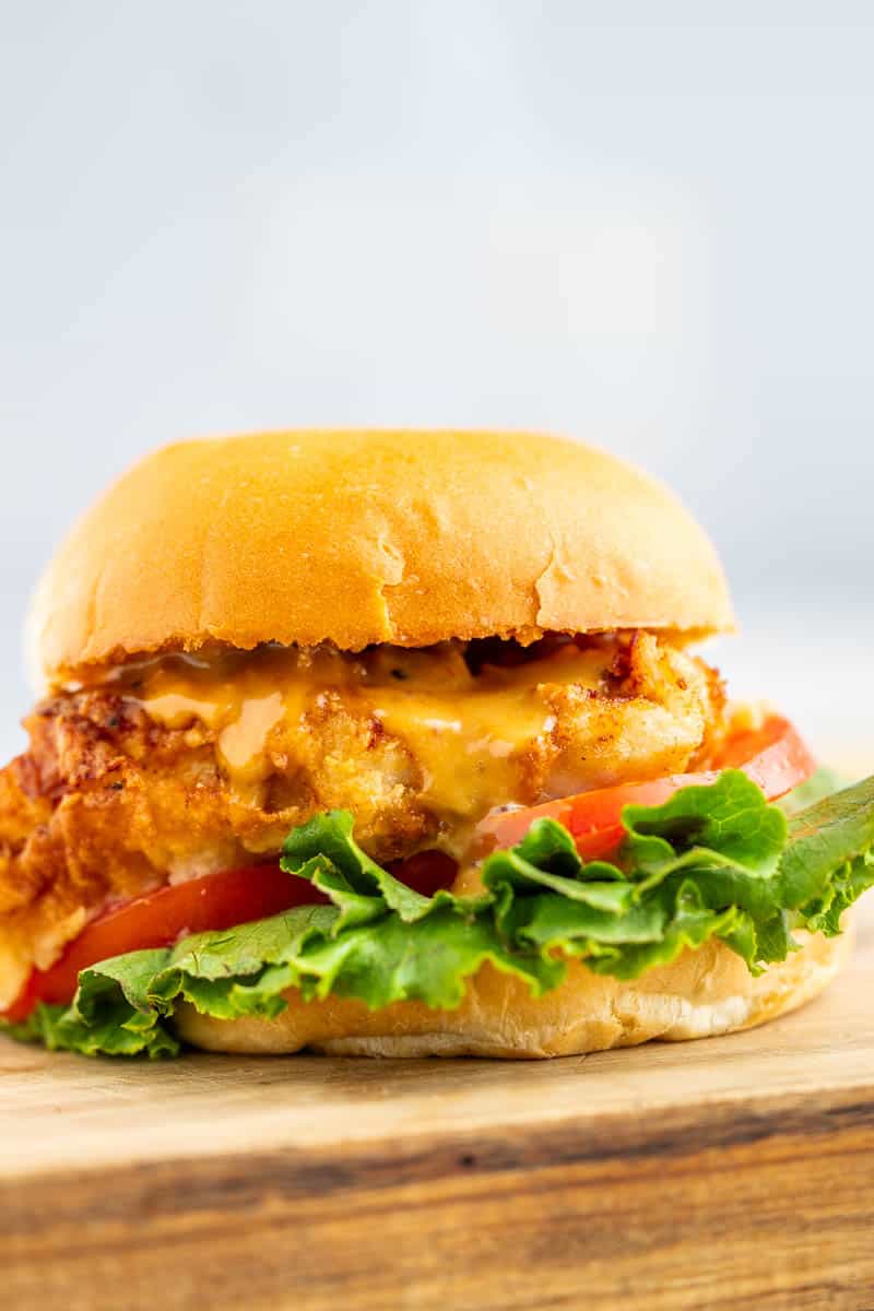 Close up view of a crispy chicken sandwich with lettuce and tomato.
