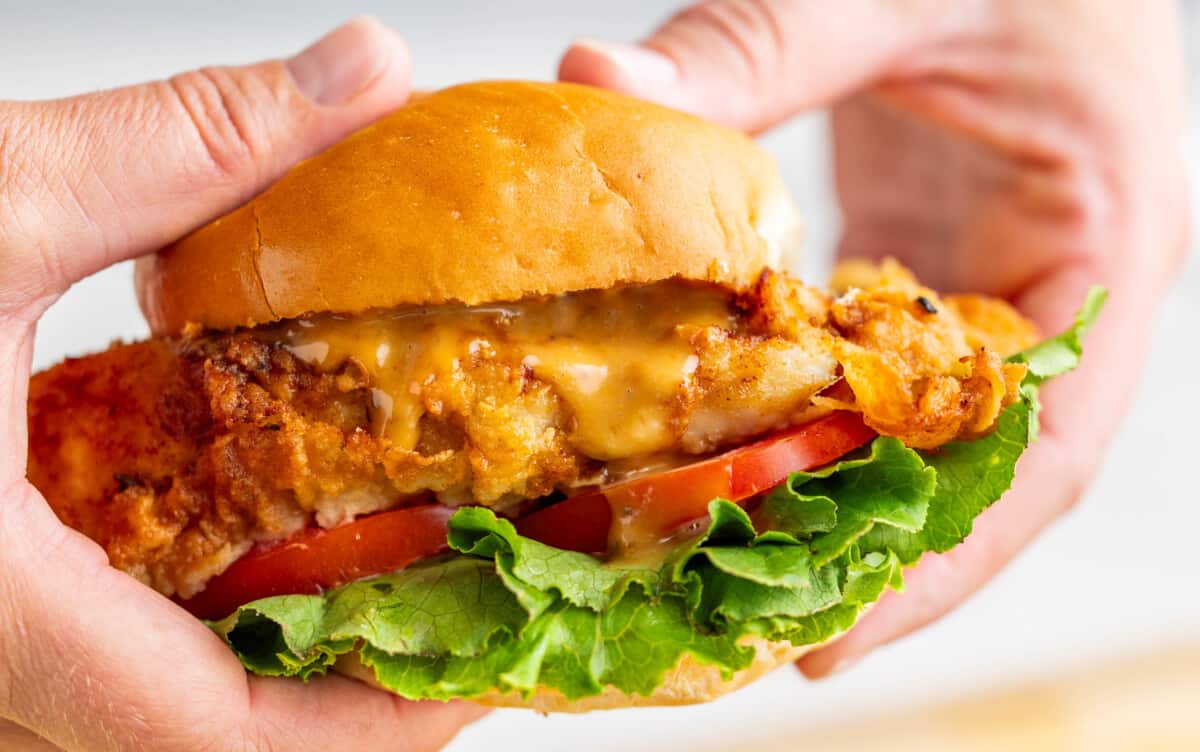 Two hands holding a crispy chicken sandwich.