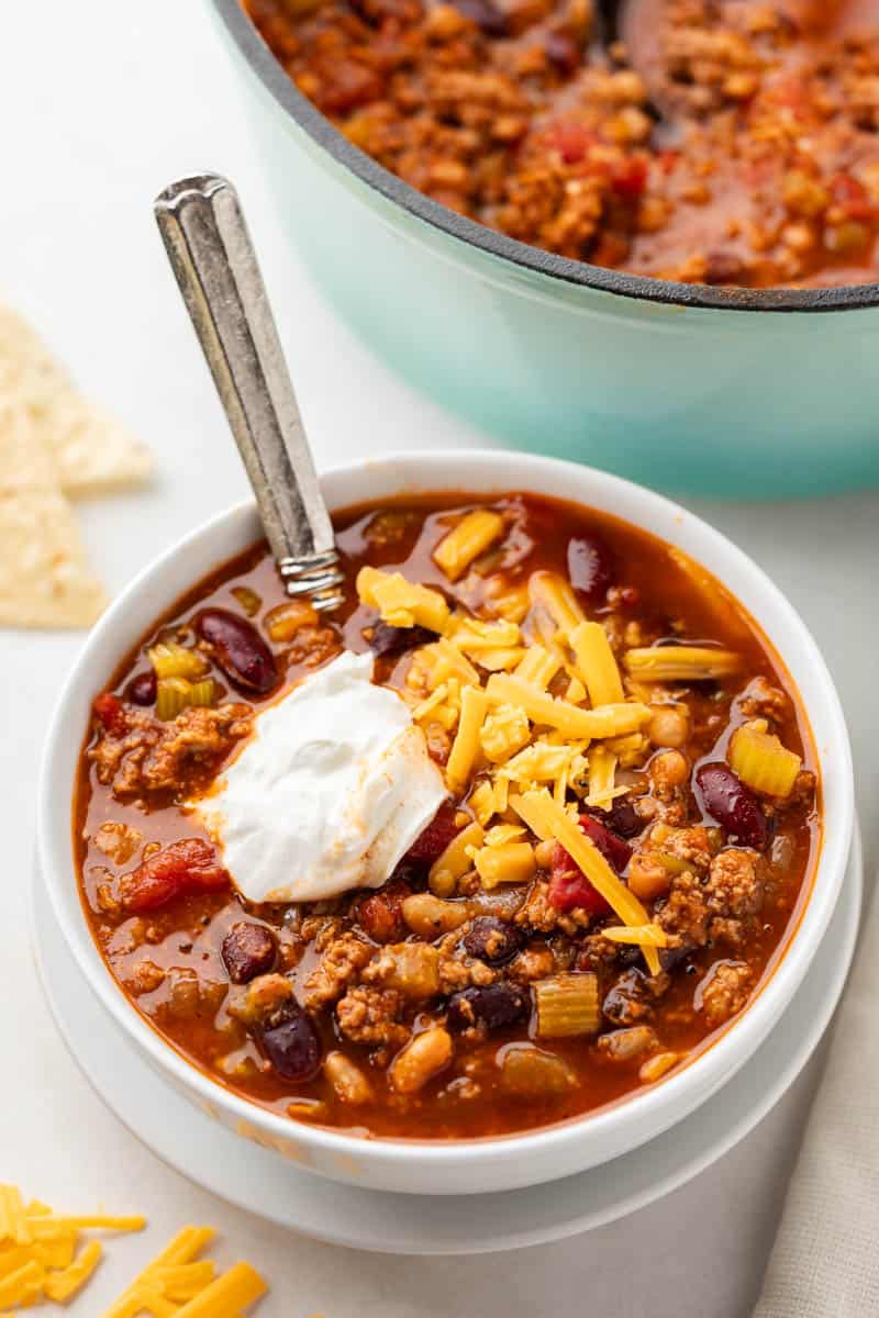 A serving of turkey chili in a white bowl with a spoon resting in the bowl.