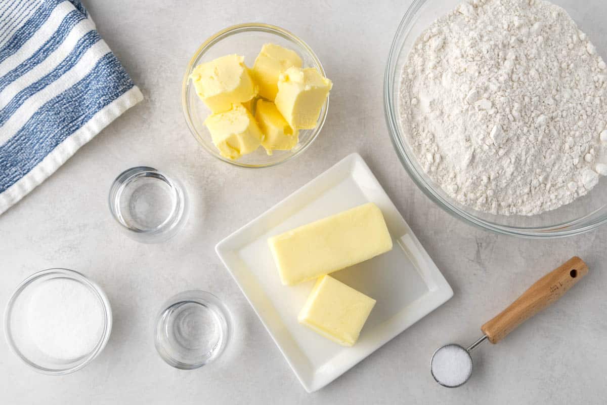 Overhead view of the raw ingredients needed to make pie crust on a clean kitchen counter.