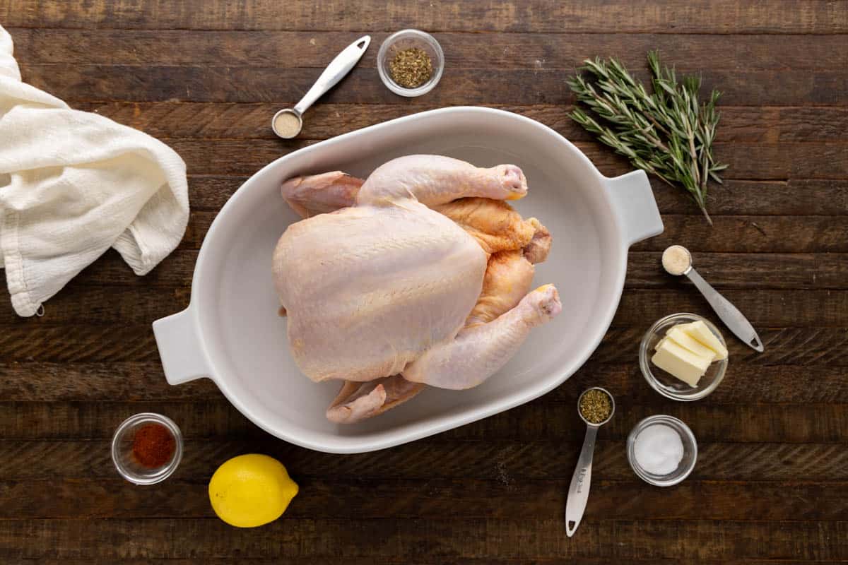 Overhead view of the raw ingredients needed to make a roasted chicken on a clean counter.