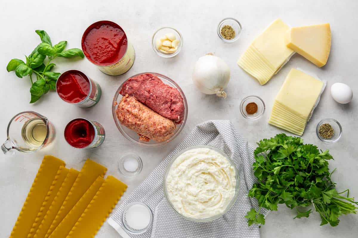 Overhead view of the raw ingredients needed to make a lasagna on a clean kitchen counter.