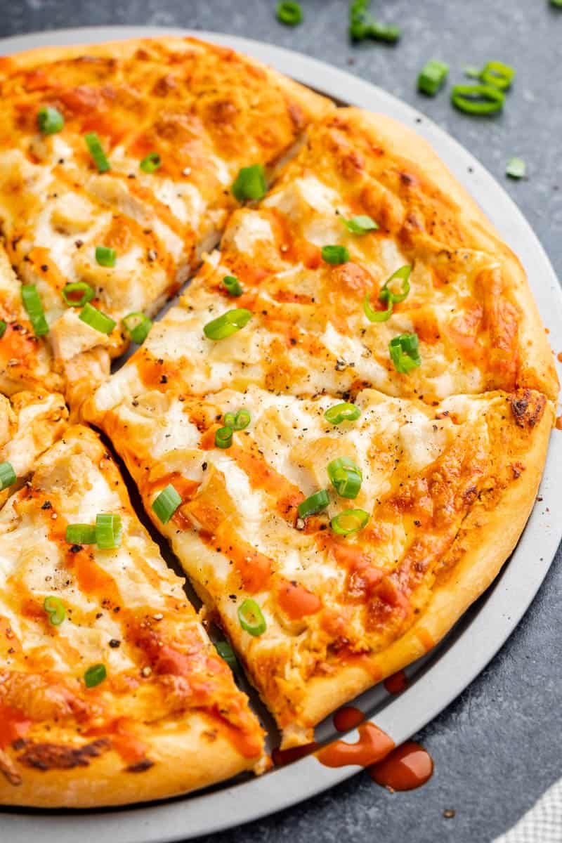 Close up view of a buffalo chicken pizza on a pizza tray.