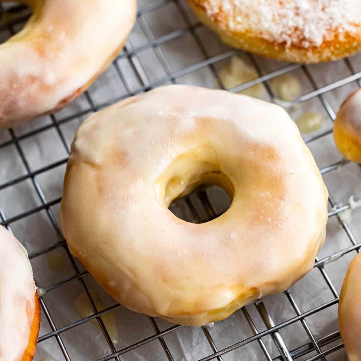 Overhead view of a glazed donut on a cooling rack.
