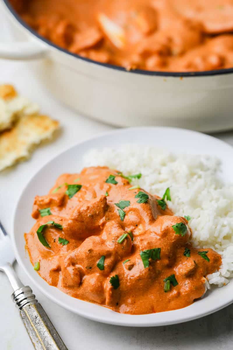 Close up view of a plate of chicken tikka masala and basmati rice with a fork resting next to the plate.