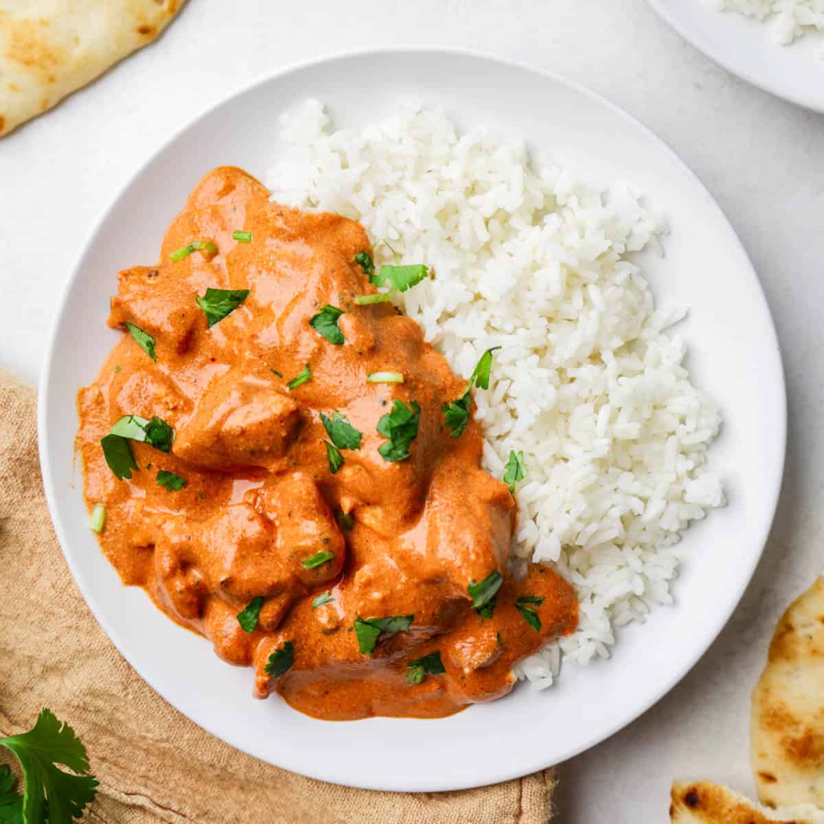 Chicken tikka masala on a white plate with fresh cilantro on top.