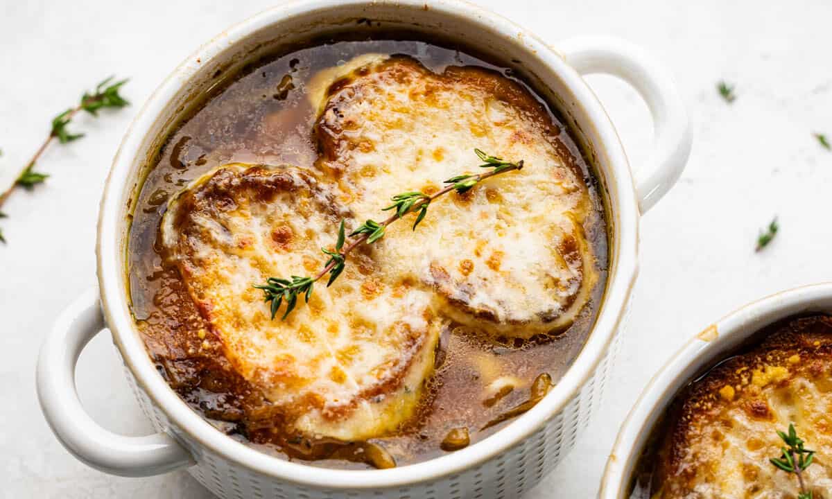French onion soup in an individual serving bowl with melted cheese on top.