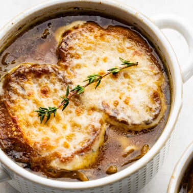 French onion soup in an individual serving bowl with melted cheese on top.