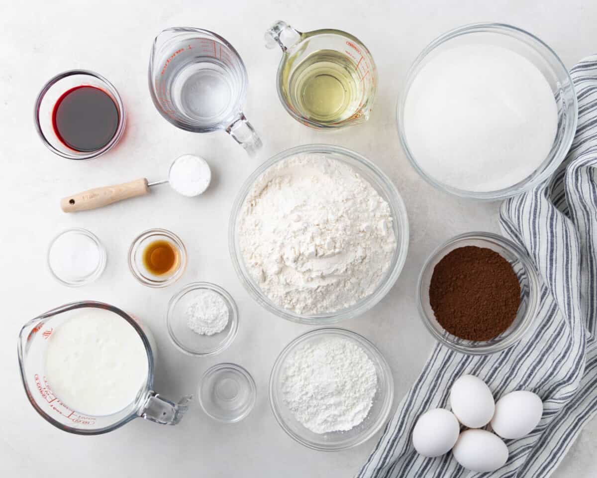 Overhead view of a clean countertop with measuring cups and bowls filled with raw baking ingredients. 