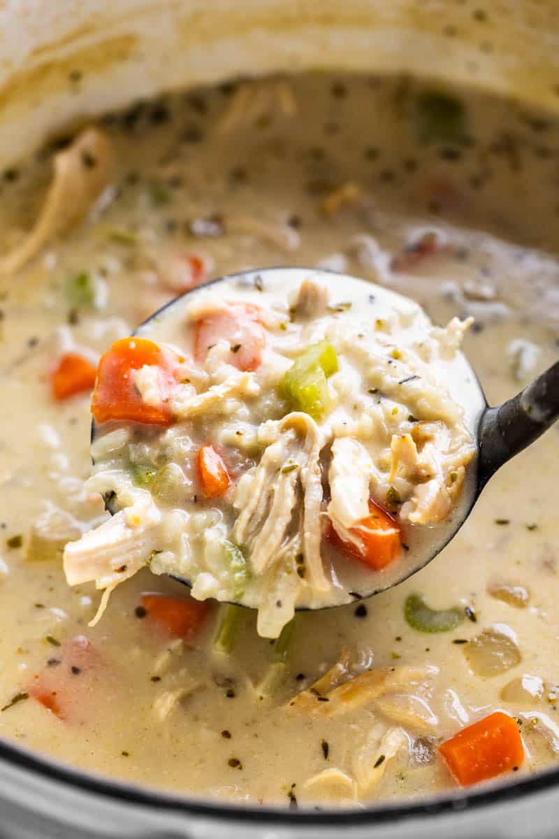 A ladle scooping out a generous helping of creamy chicken and rice soup.