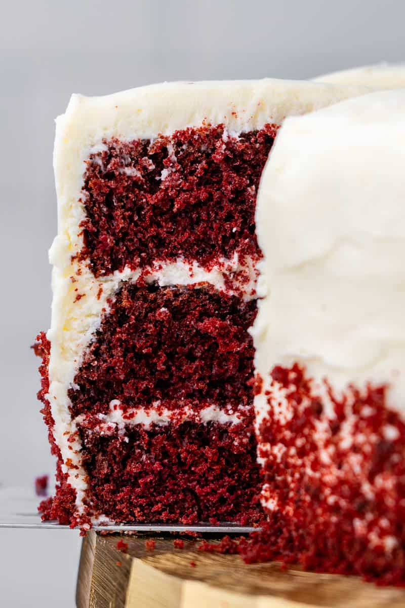 Close up view of a slice of red velvet cake being pulled from the whole cake.