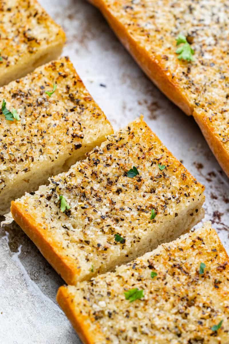 Overhead view of garlic bread on a baking sheet that has been cut into slices.