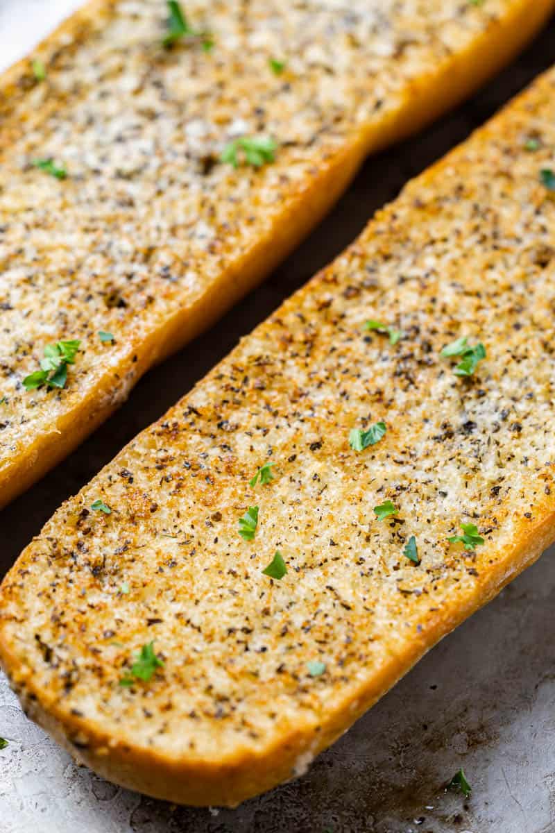 Close up view of homemade garlic bread with parsley on top.