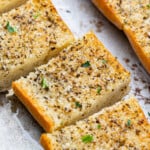 Close up view of garlic bread on a baking sheet with fresh parsley.