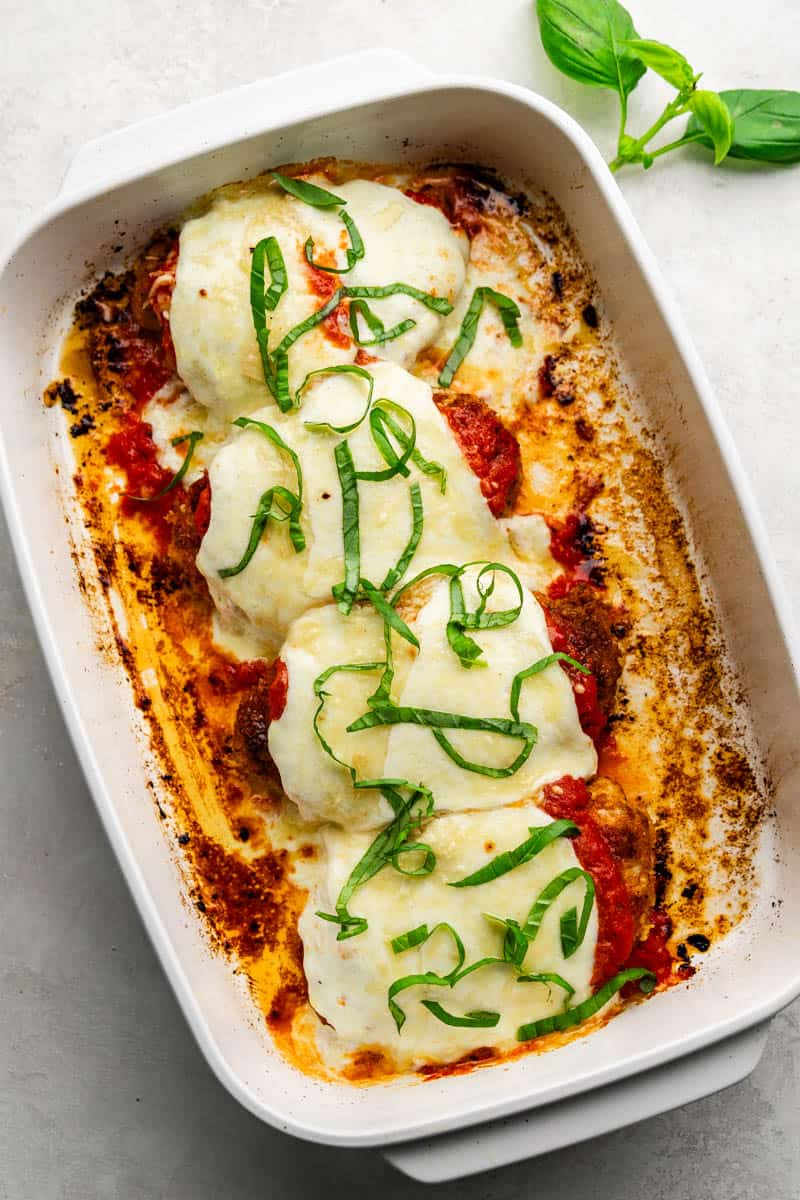 An overhead birds-eye view of a pan of baked chicken parmesan topped with melted mozzarella cheese.