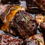 A close up view of braised beef short ribs in braising juices.