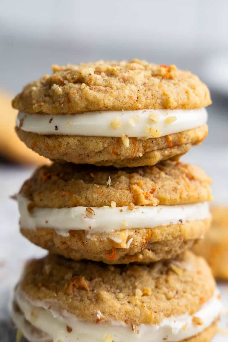 A stack of carrot cake cookie sandwiches with cream cheese frosting.
