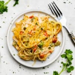 An overhead view of a plate of chicken spaghetti with a fork sitting by ready to eat.