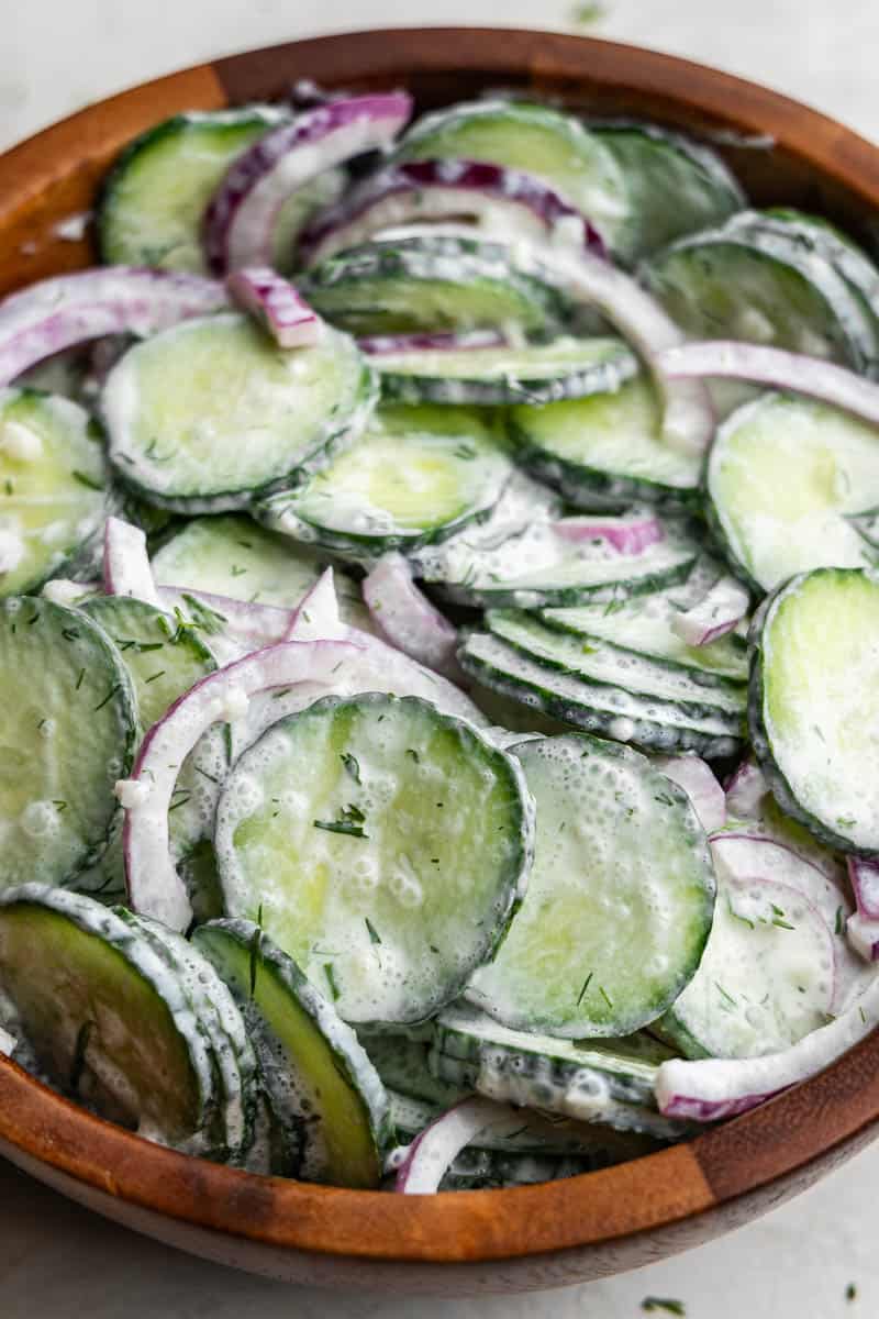 A close up view of a bowl of creamy-style cucumber salad.