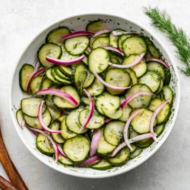 An overhead birds-eye view of a bowl of a vinegar-based German-style cucumber salad.