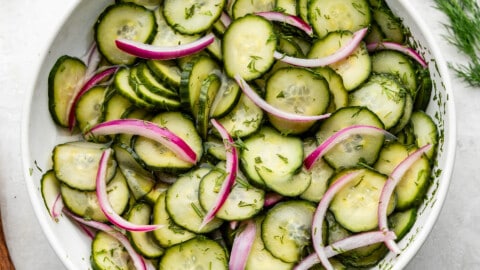 An overhead birds-eye view of a bowl of a vinegar-based German-style cucumber salad.