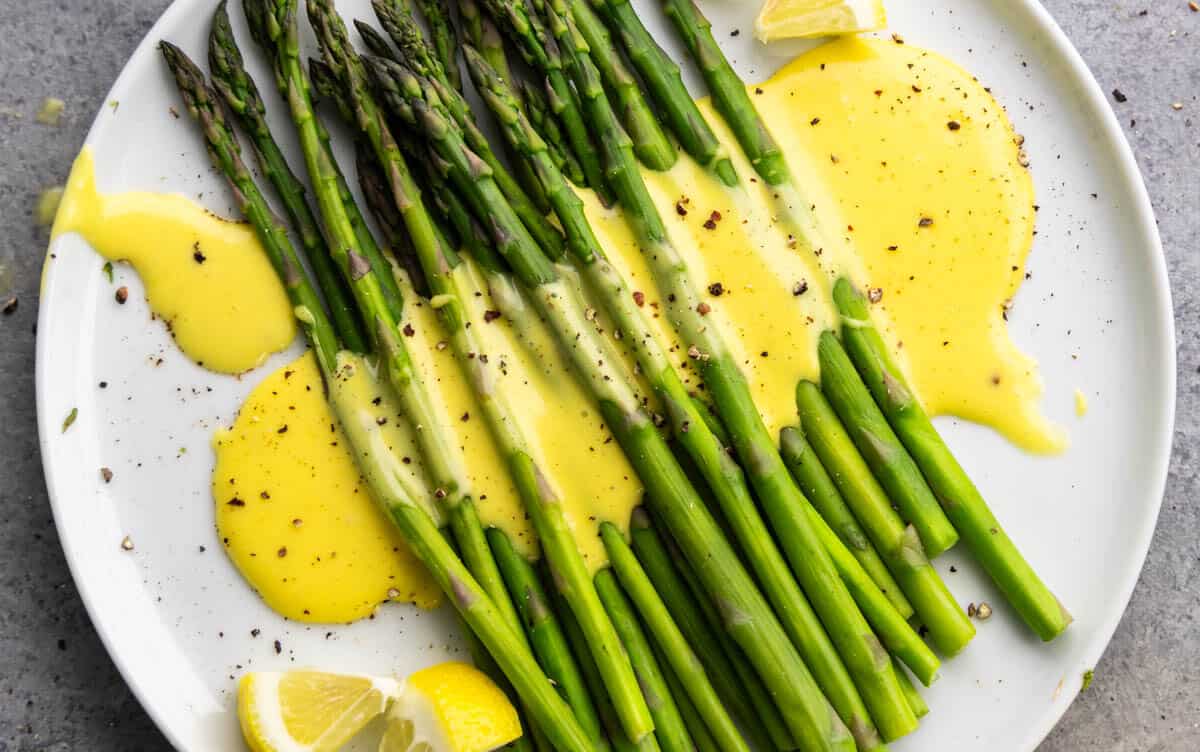 Overhead view of asparagus with hollandaise sauce drizzled on top.