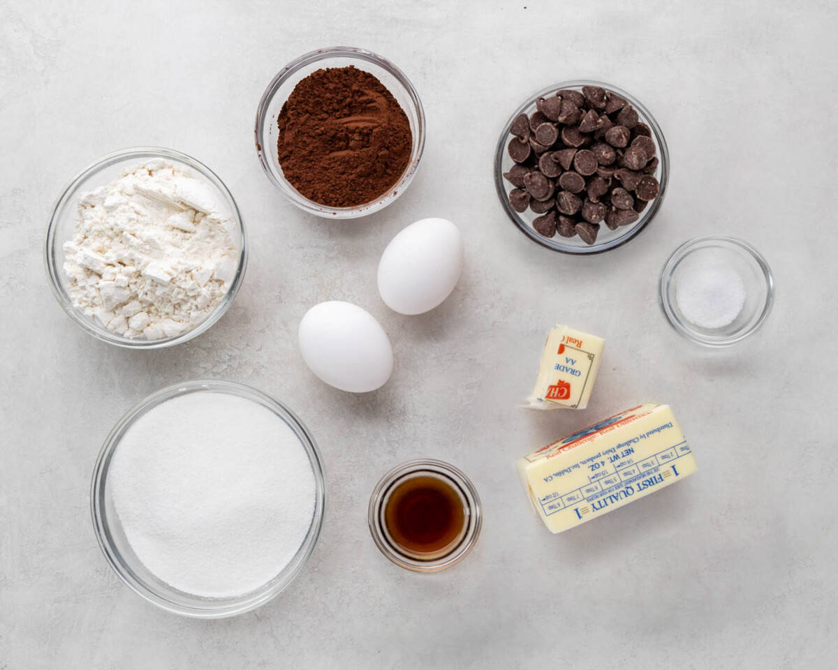Overhead view of measured out flour, sugar, cocoa powder, chocolate chips, eggs, butter, and salt.