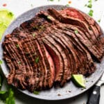 An overhead view of a plate of sliced carne asada straight off the grill.