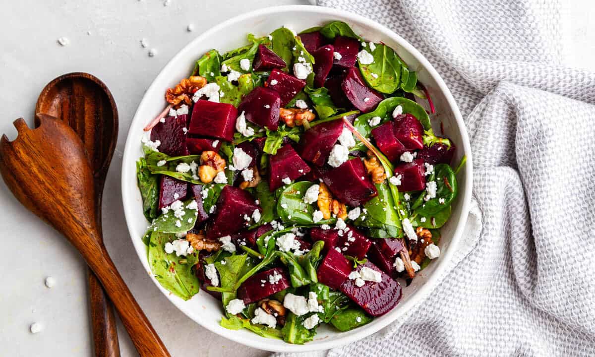 An overhead birds-eye view of a bowl of beet salad with nuts and feta cheese crumbles.
