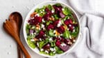 An overhead birds-eye view of a bowl of beet salad with nuts and feta cheese crumbles.