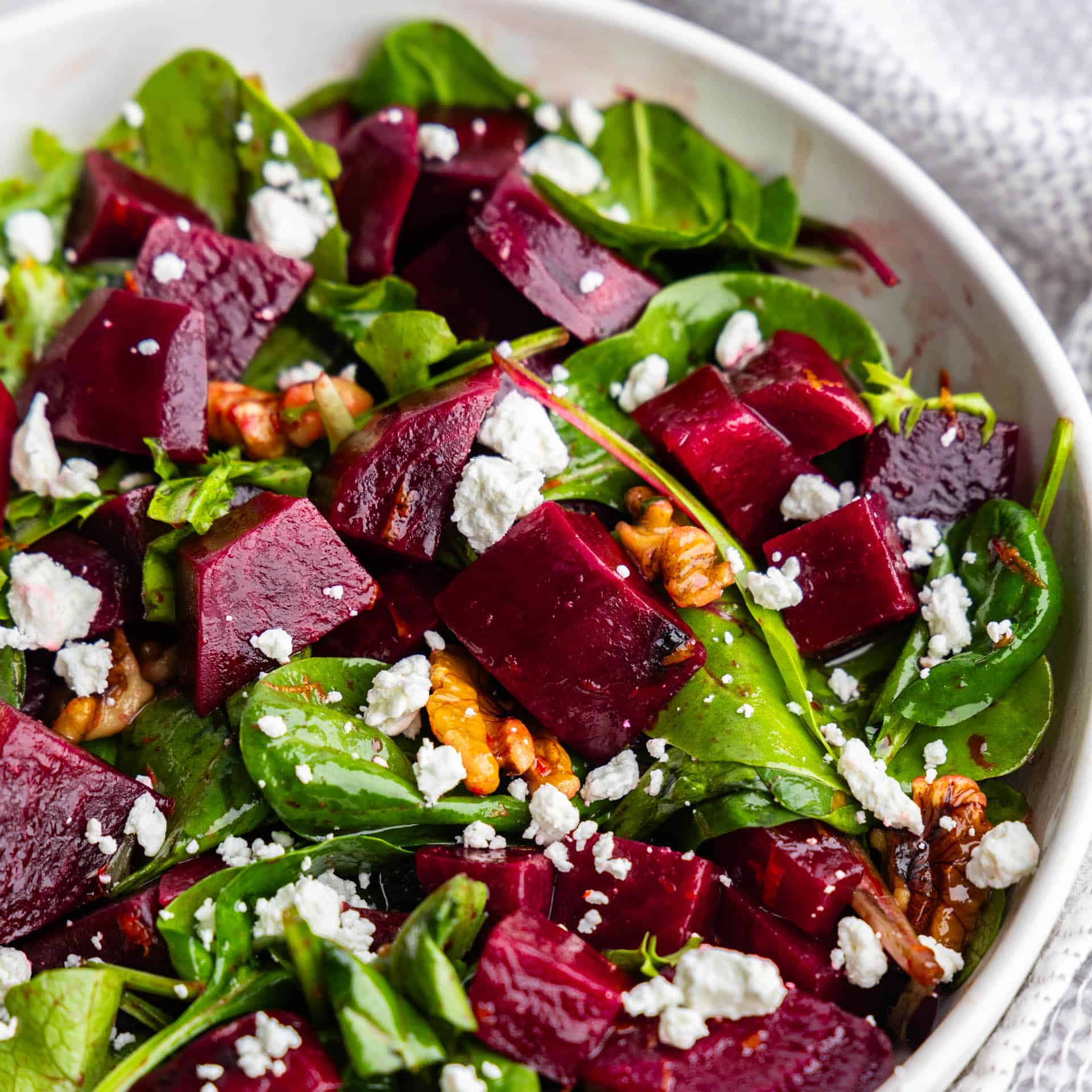 Close up view of a white bowl full of beet salad.
