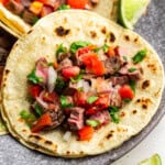 A close up view of a carne asada taco in a corn tortilla.