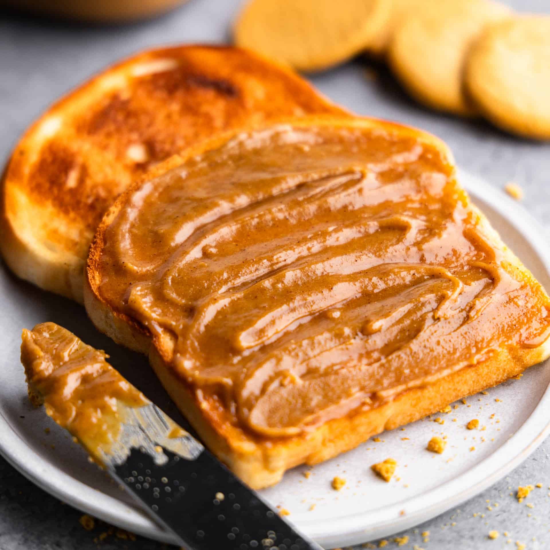 A close up view of two slices of toast on a plate with homemade cookie butter spread on top.