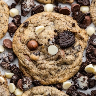 A close up view of cookies and cream cookies surrounded by cookie bits and chocolate chips.