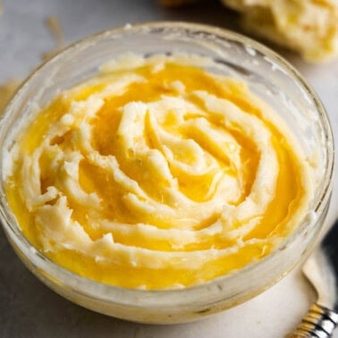 A close up view of a glass bowl filled with honey butter.