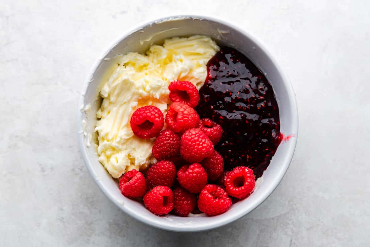 An overhead view of a bowl of ingredients for homemade raspberry butter.