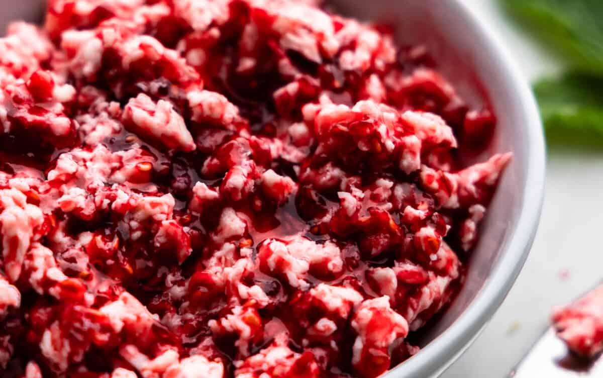 A close up view of raspberry butter in a white bowl.