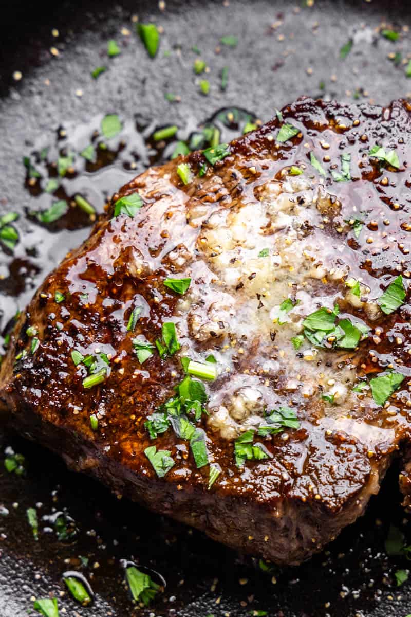 A close up view of a filet mignon topped with garlic butter. 