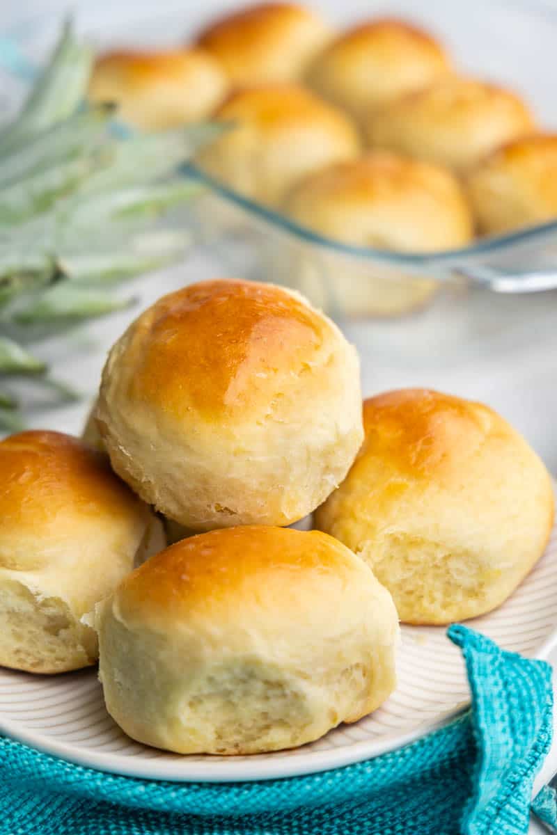 A pile of four freshly baked rolls on a plate. 