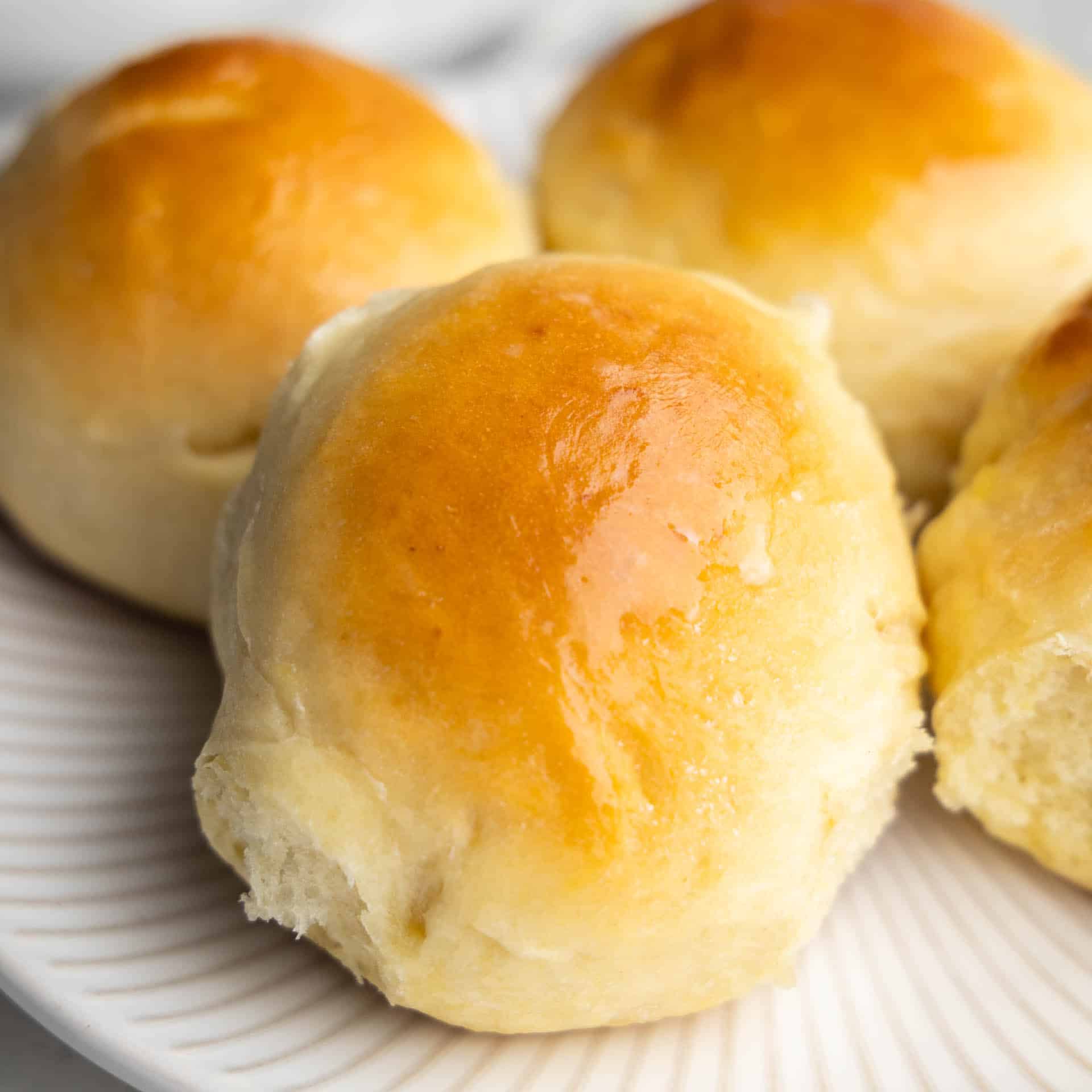 A close up view of hawaiian sweet rolls on a white plate.