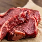 Two ribeye steaks sitting on a sheet of brown parchment paper.