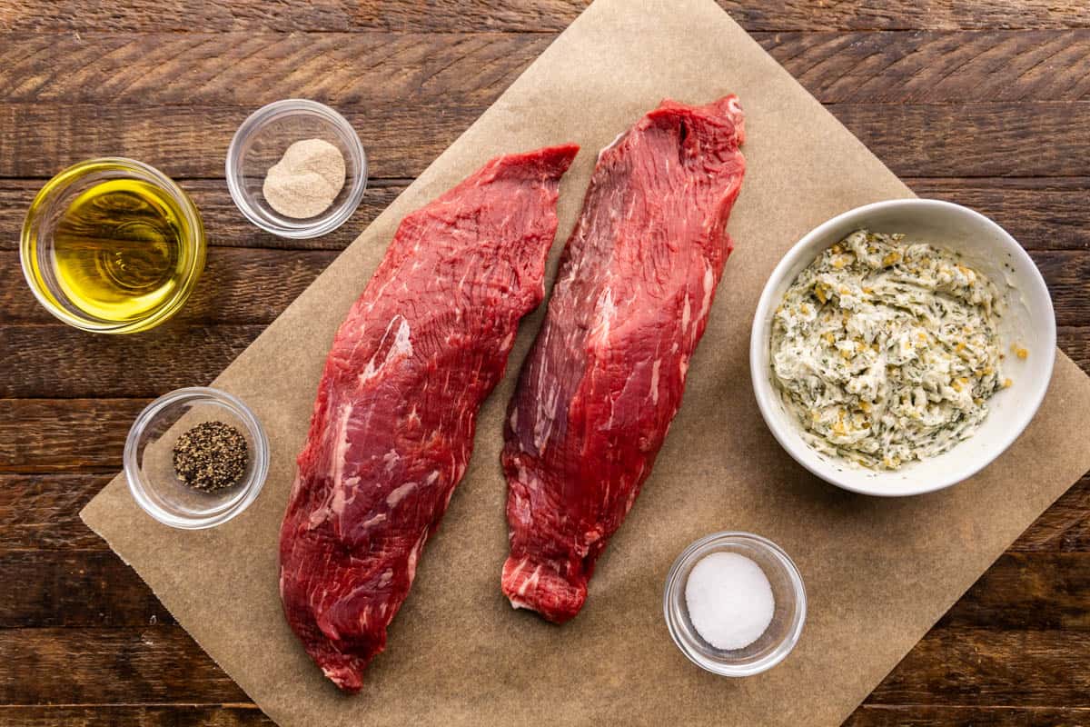 An overhead view of the ingredients needed to make a petite tender steak including resting butter, salt, pepper, and oil.