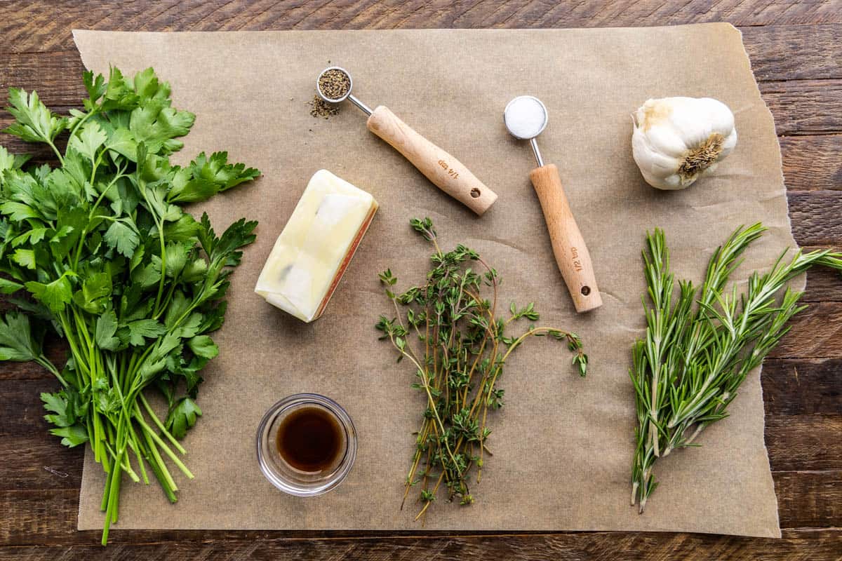 An overhead view of the ingredients needed to make a compound resting butter including butter, herbs, garlic, and seasonings.