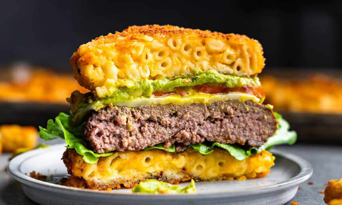 A close up view of a burger where the buns are made out of fried mac and cheese.