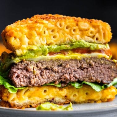A close up view of a burger where the buns are made out of fried mac and cheese.