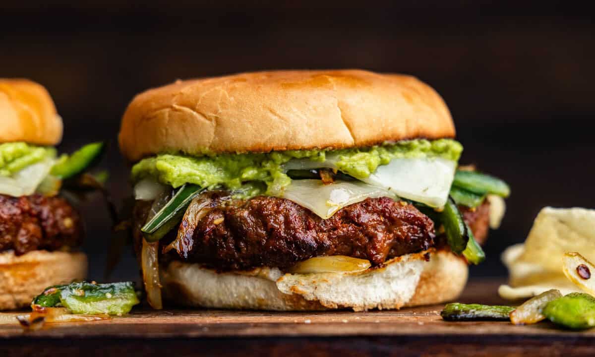 A queso fundido chorizo burger on a wooden platter for serving.