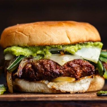 A queso fundido chorizo burger on a wooden platter for serving.